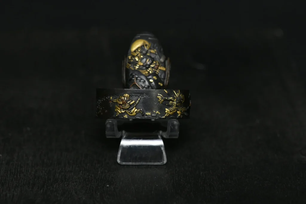Fuchi-kashira de shakudō con escena figurativa