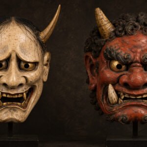 Illustratie van een bleek Hannya-masker naast een rood Oni-masker, met nadruk op hun contrasterende gelaatstrekken.