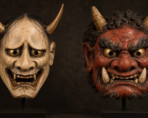 Illustration of a pale Hannya mask beside a red Oni mask, highlighting their contrasting facial features.